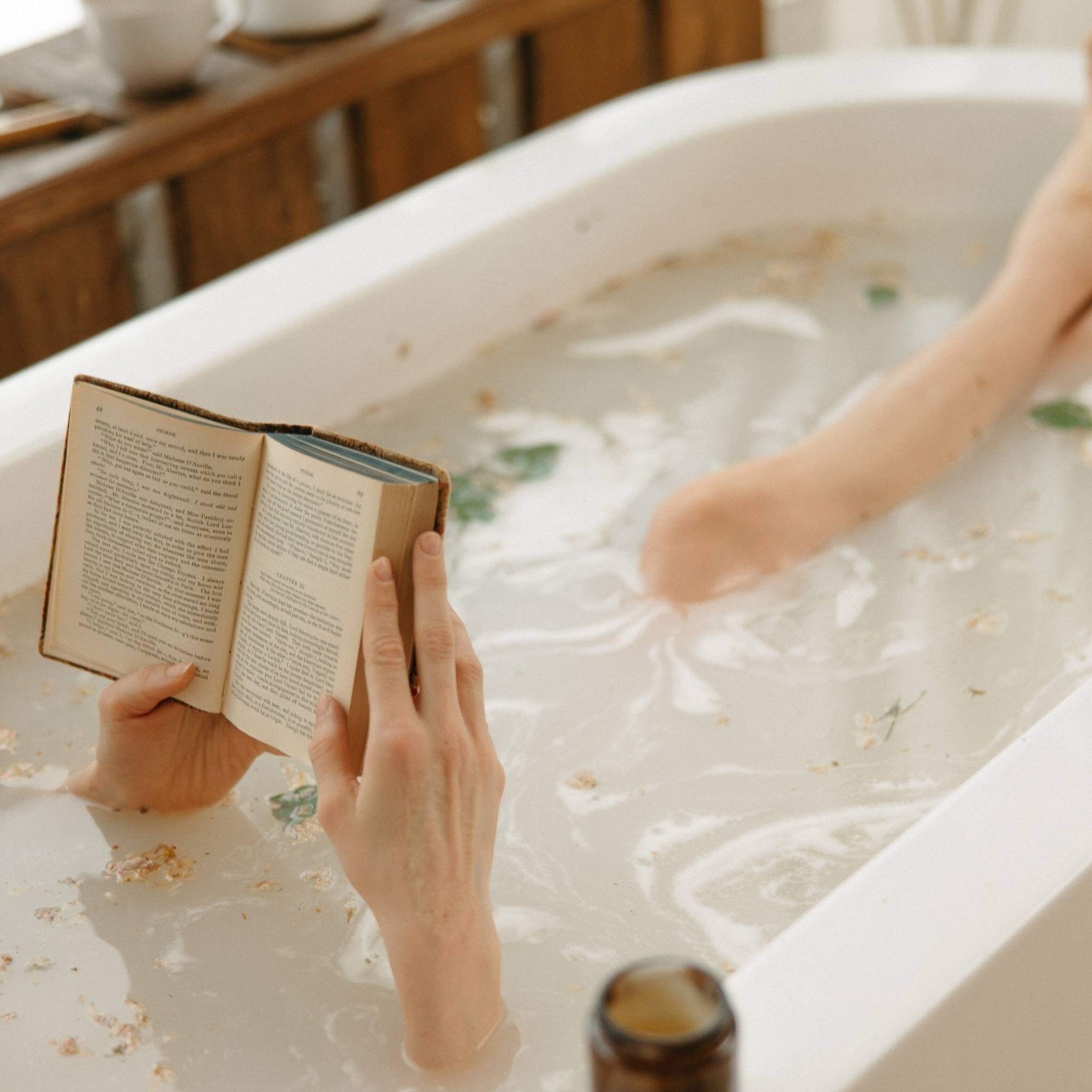 Lady reading and relaxing in the bath as part of her self-care routine