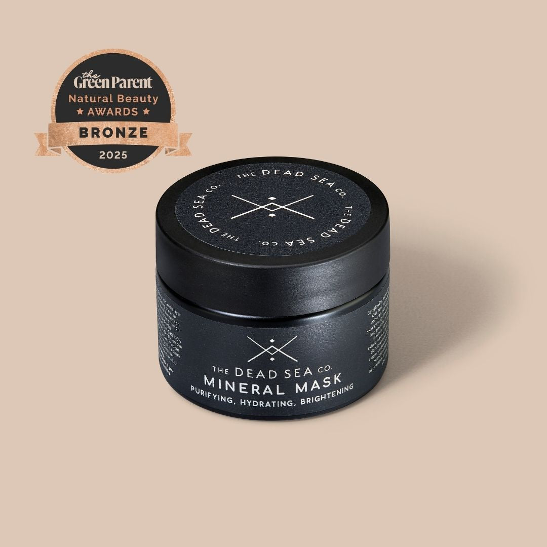 Black jar of The Dead Sea Co. Mineral Mask with bronze award badge on beige background