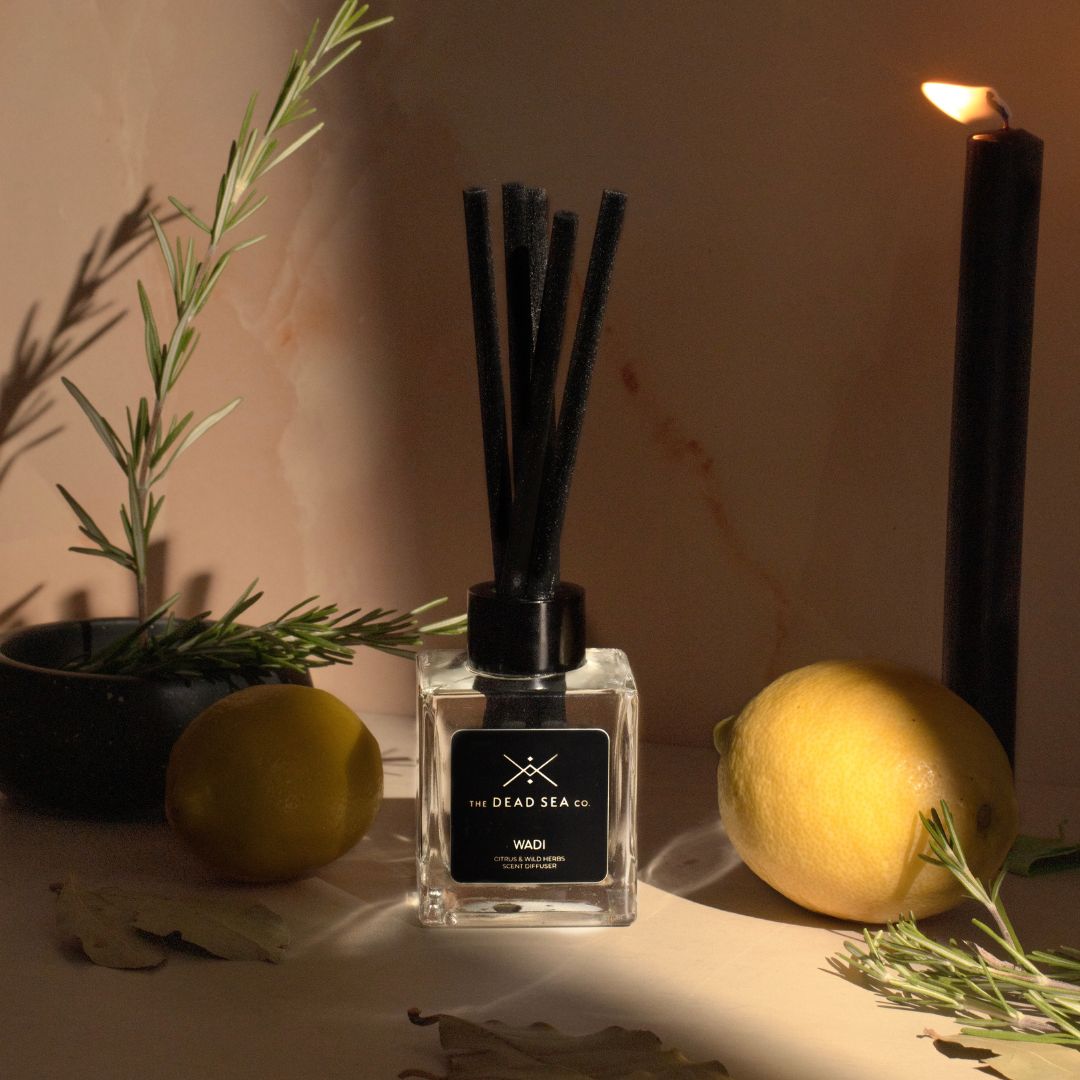The Dead Sea Co. Citrus & Wild Herb Reed Diffuser in a serene setting, surrounded by fresh citrus fruits and aromatic herbs.