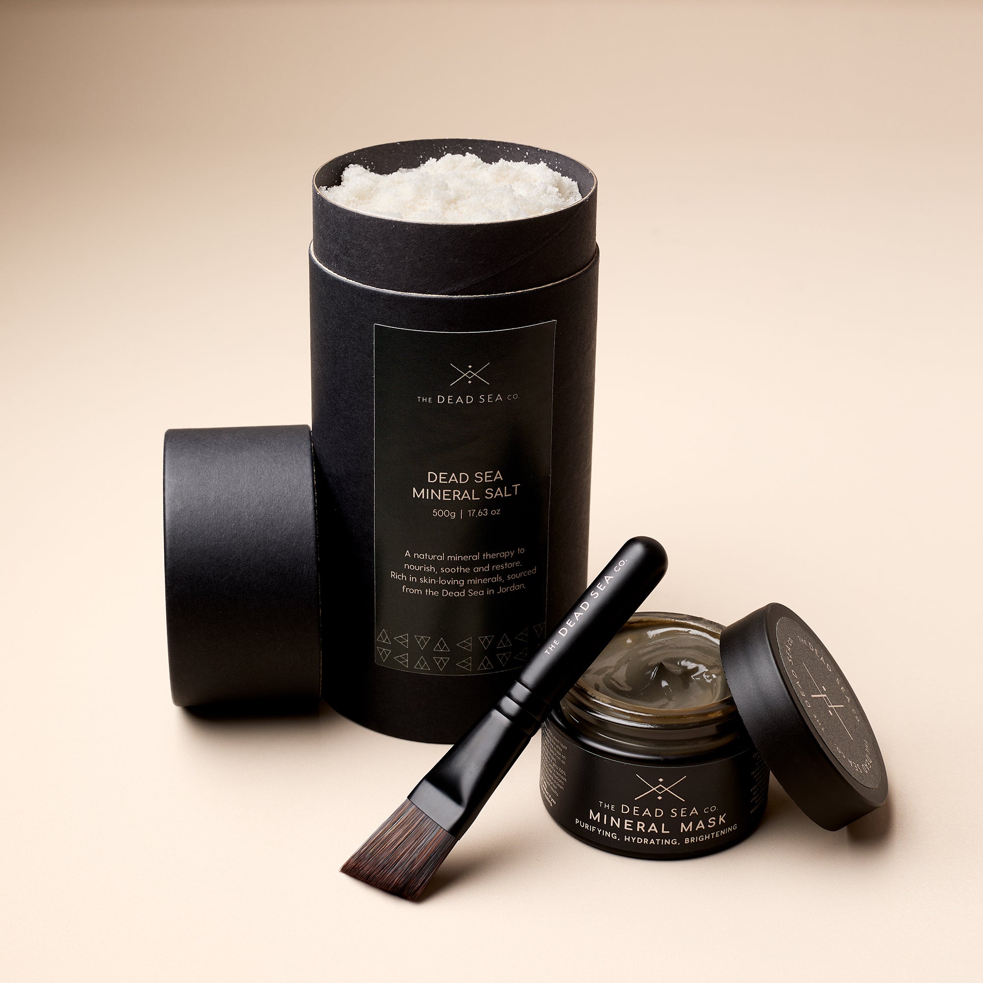 The Dead Sea Co. Mineral Ritual Spa Set showing product textures, open mineral salt and mineral mud mask with applicator brush, highlighting clean, therapeutic skincare.