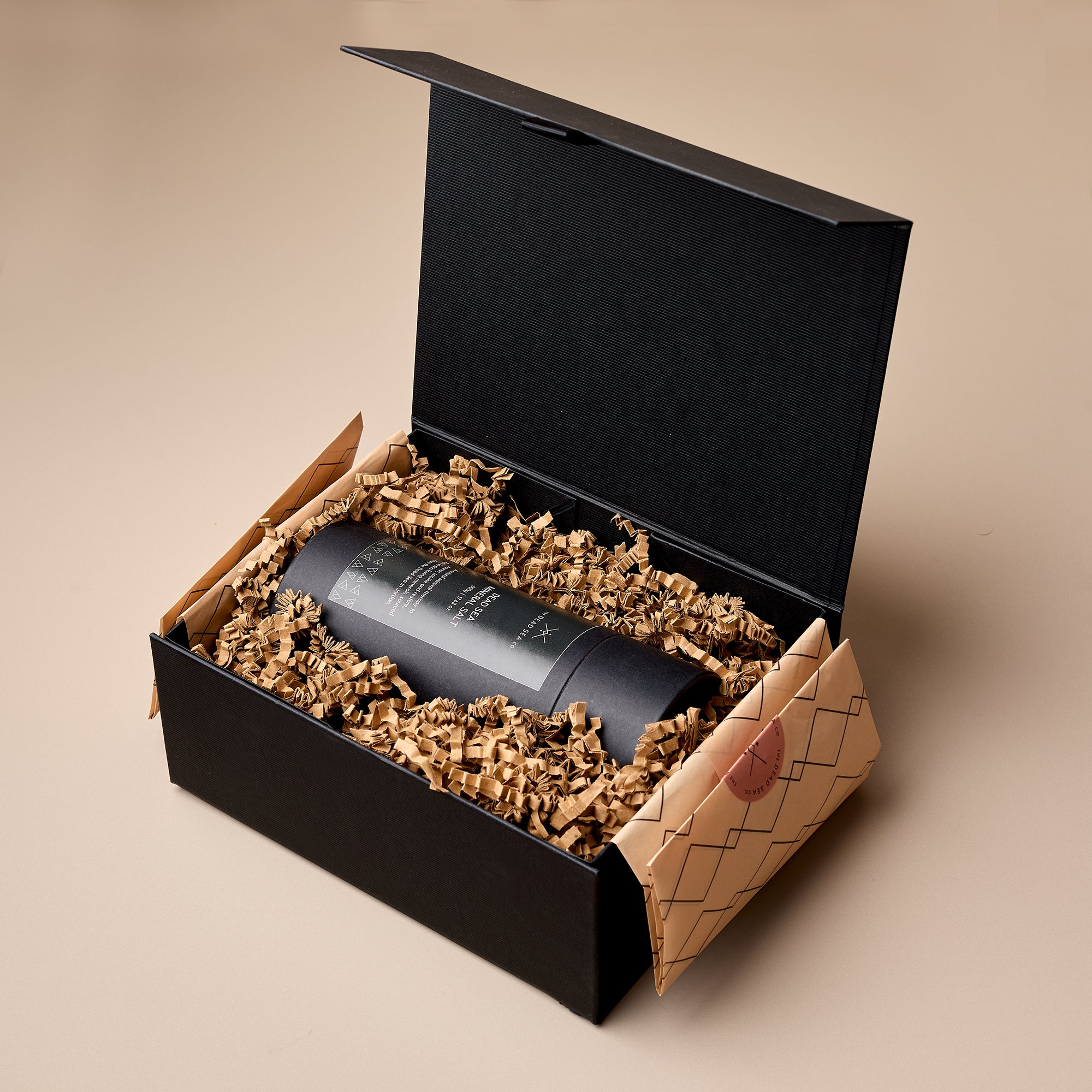 The Dead Sea Co. Mineral Salt presented in a luxury black magnetic gift box, nestled in eco-friendly shredded packing paper.