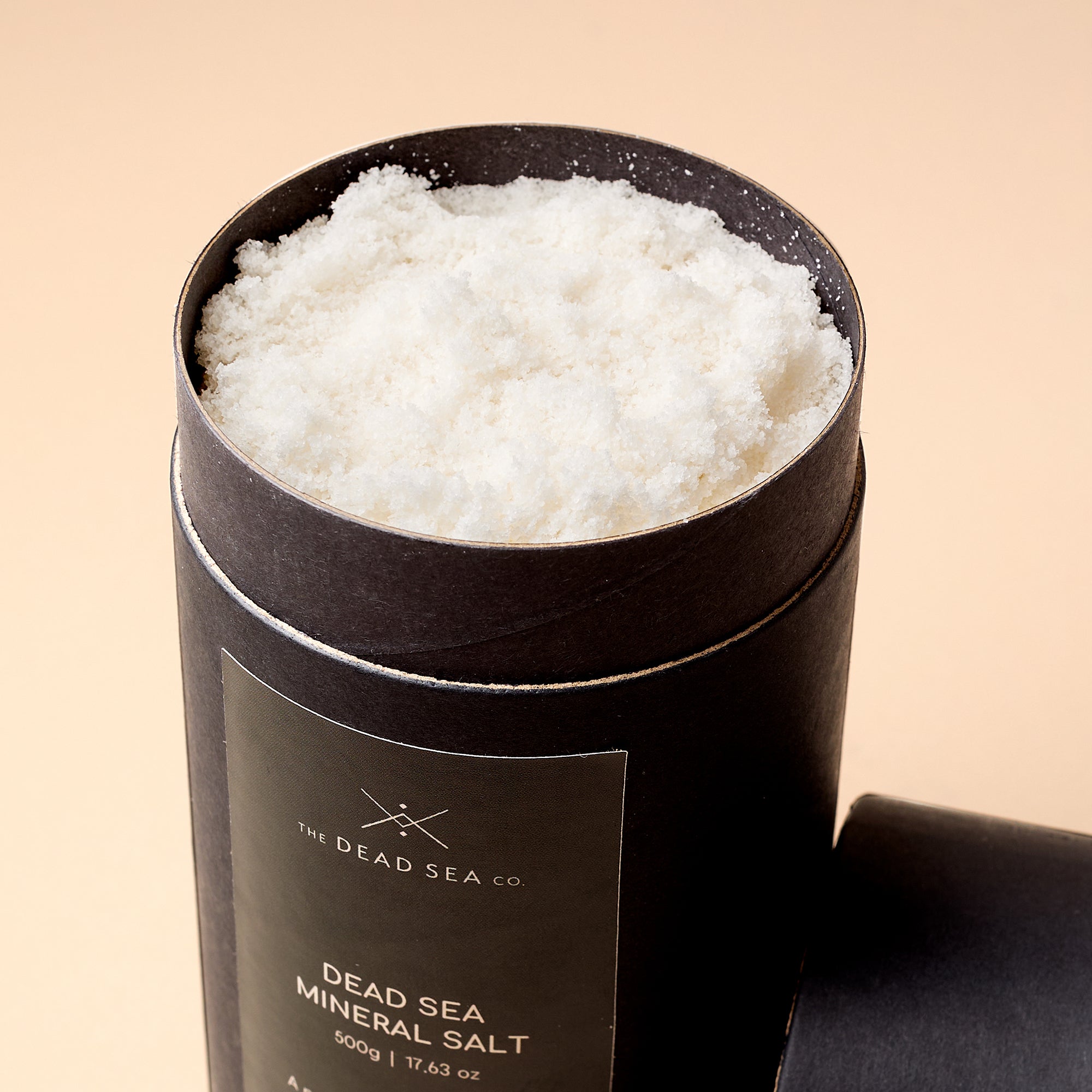 Close-up of open Dead Sea Co. Mineral Salt container showing fine-textured natural salt crystals—rich in therapeutic minerals for detox and relaxation.
