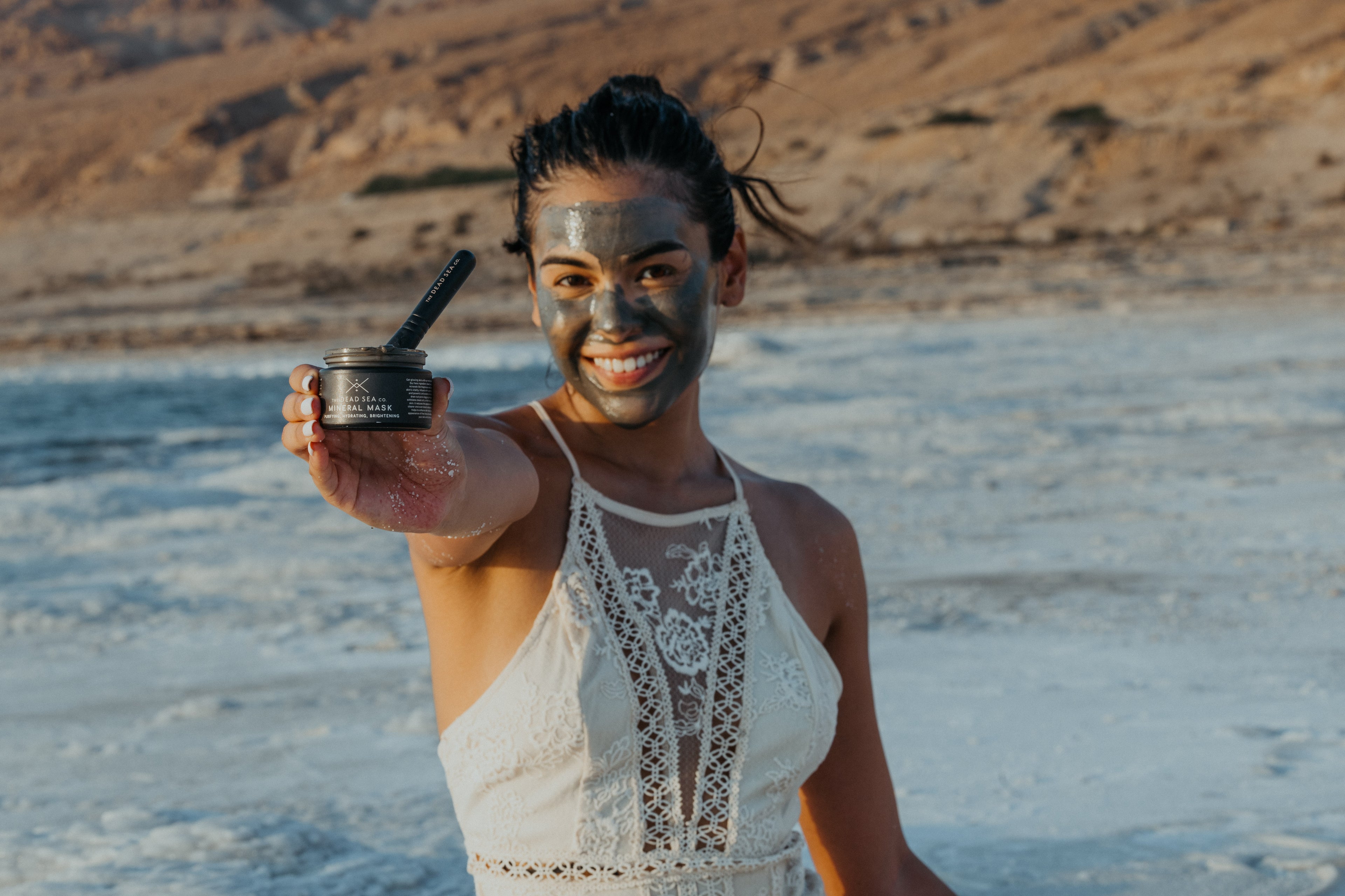 A woman at the Dead Sea in Jordan using The Dead Sea Co. Mineral Mask and brush