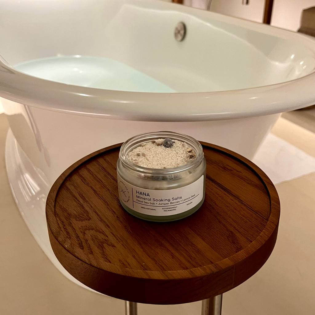 Bath salt jar with lid open showing Dead Sea salt, juniper berries and dried lemon peel