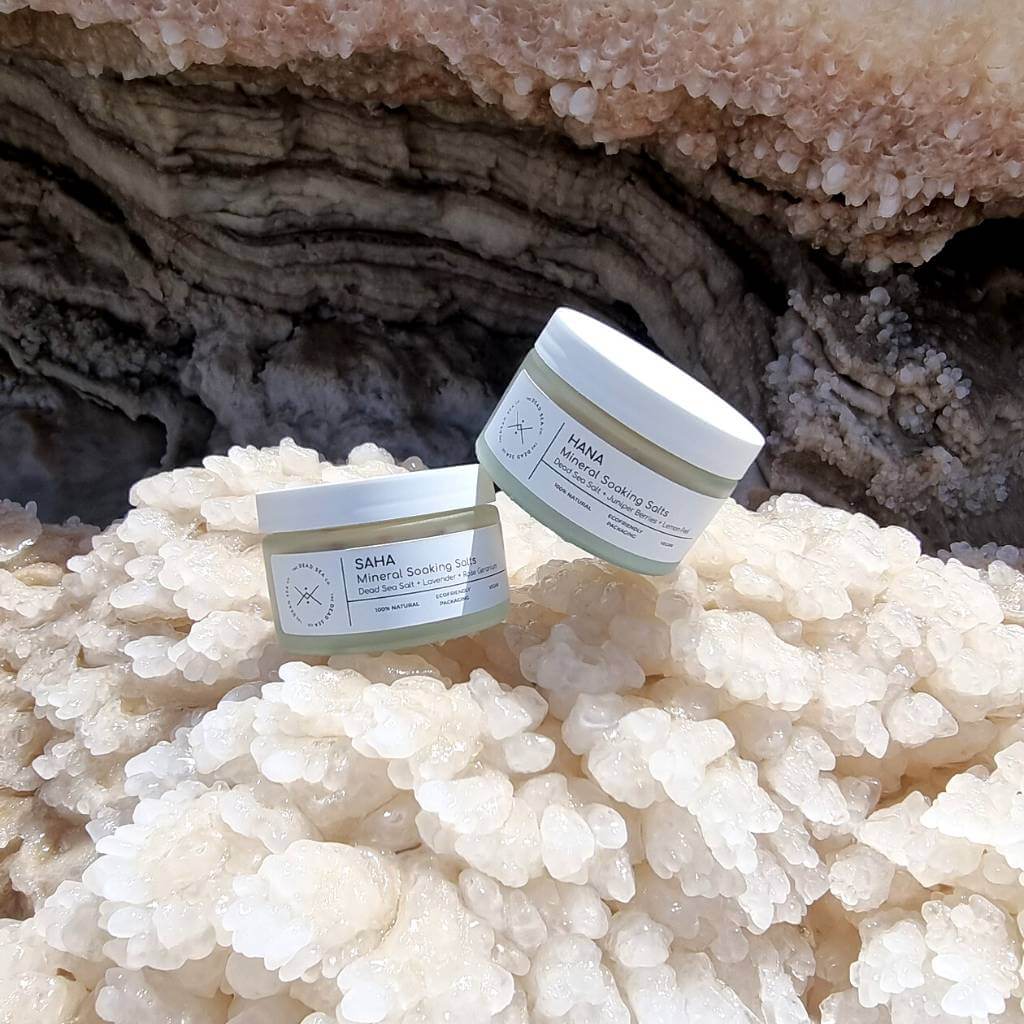 Two different scents of Dead Sea bath salts sitting on Dead Sea Salt at the Dead Sea