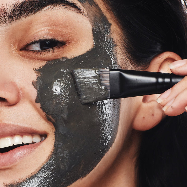Self-care time: woman using the angled brush to apply The Dead Sea Co.'s natural Dead Sea mineral mask.