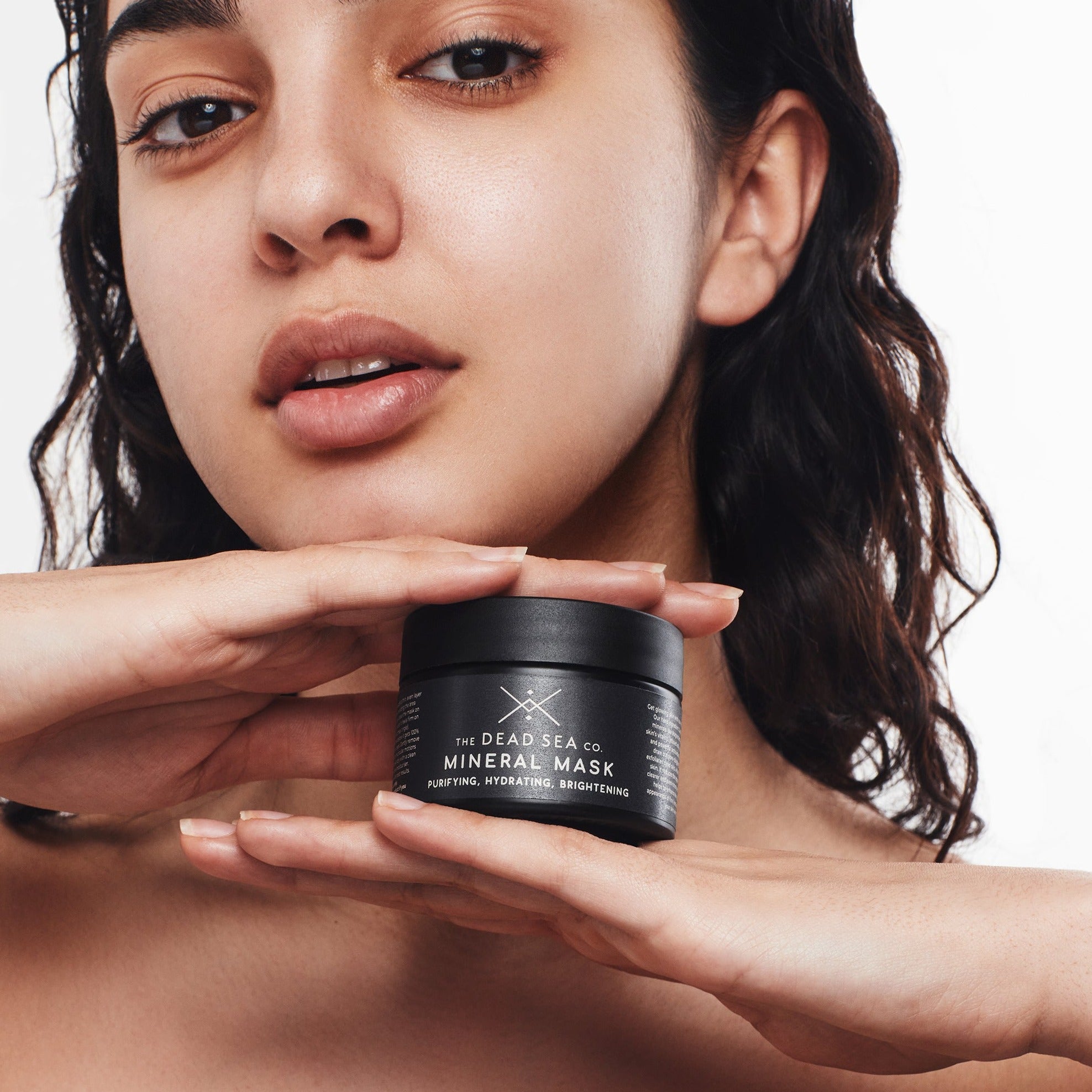 Woman holding The Dead Sea Co. Mineral Mud Mask